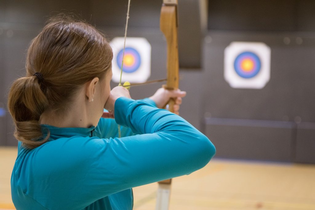 Girl shooting arrow at target